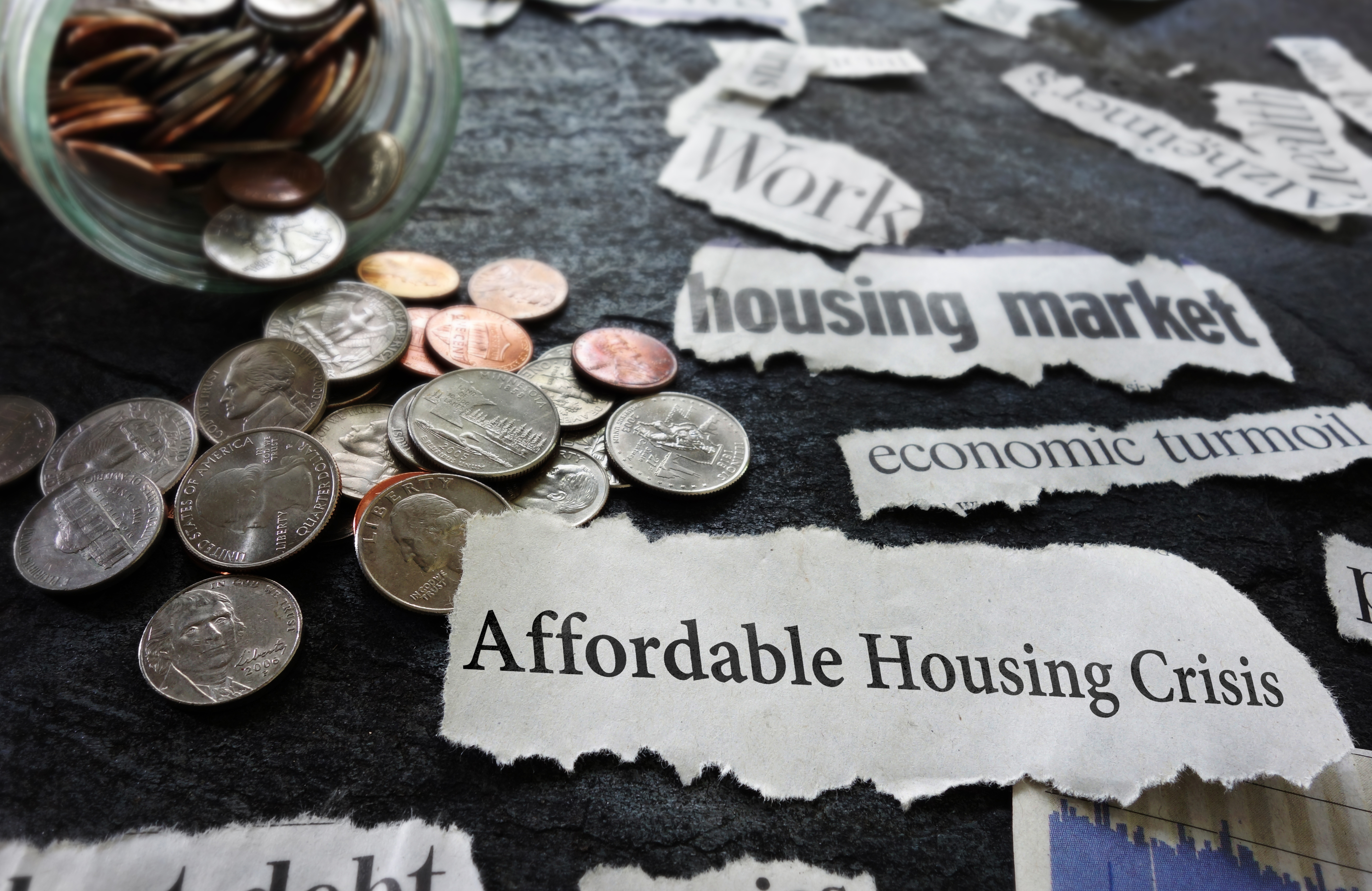 Photo of change and newspaper clippings saying affordable housing crisis